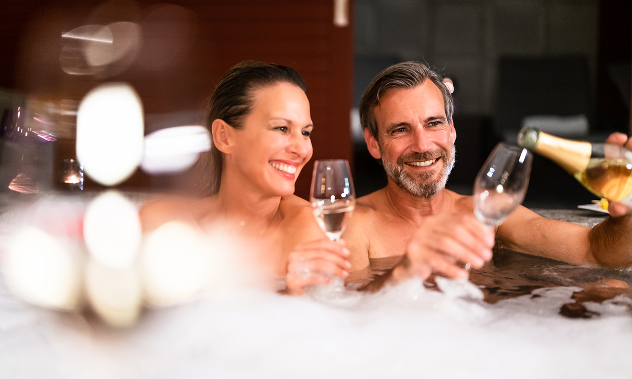 Ein Paar stößt im Spa-Bereich mit Sekt im Gräflichen Park an