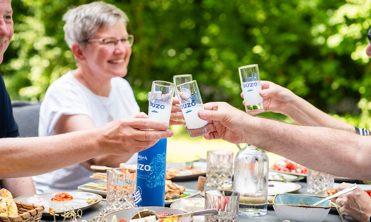 Personen stoßen mit Ouzo an